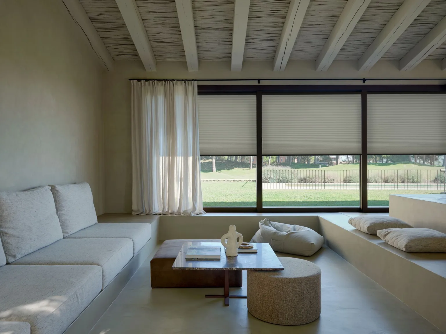 Plisse alb pe o fereastră panoramică de living, alături de o perdea din in